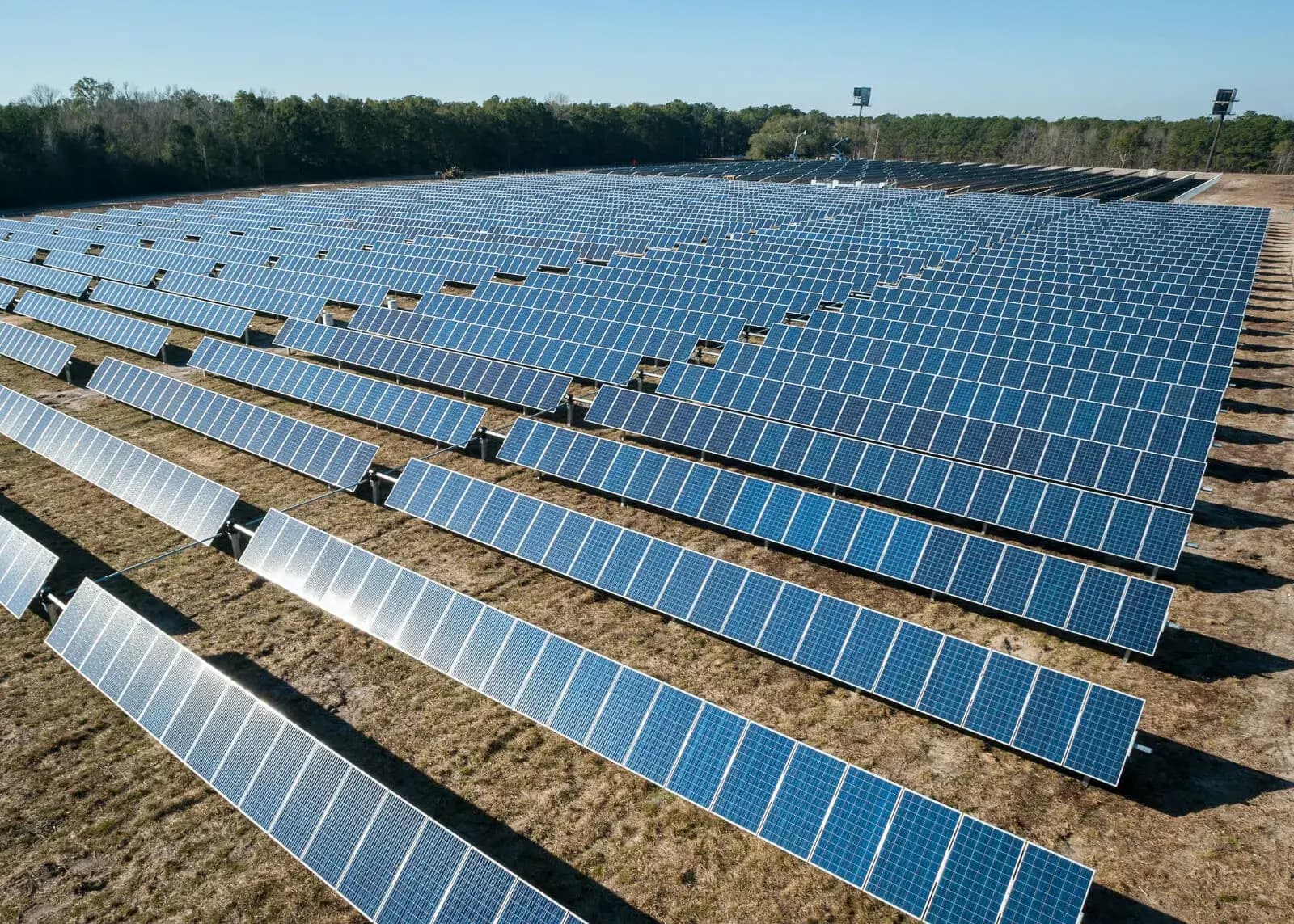 A bright sun shining over a house with solar panels installed on the roof, symbolizing the harmonious relationship between solar installations and traditional energy providers.